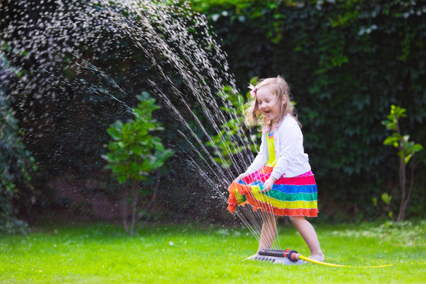 孩子们在花园里玩洒水器图片下载