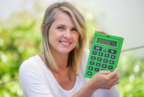 迷人的微笑女人与计算器孤立在绿色背景图片下载