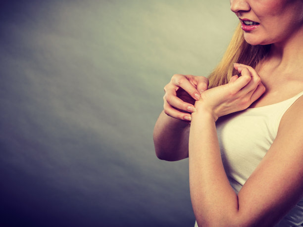 一个女人用过敏皮疹挠她发痒的手腕图片下载