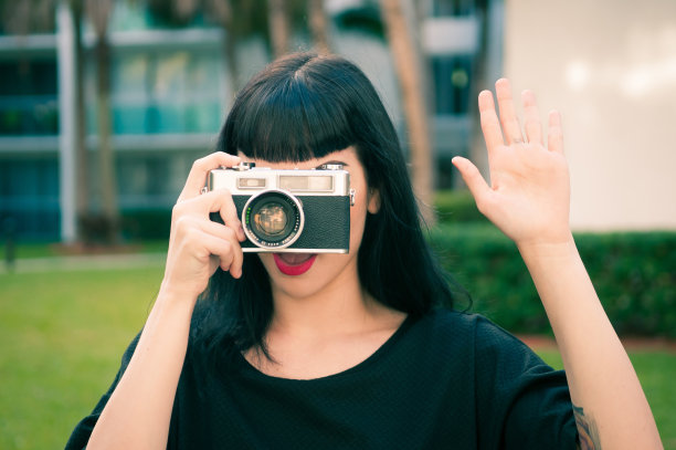 美丽的年轻女子用老式胶卷相机拍照图片下载