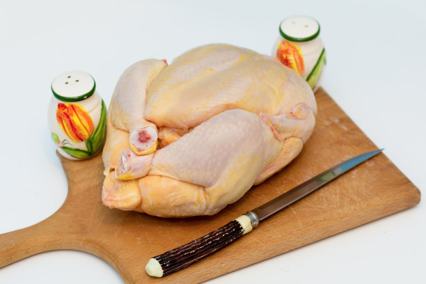 用菜刀切在老式砧板上的生整鸡图片下载