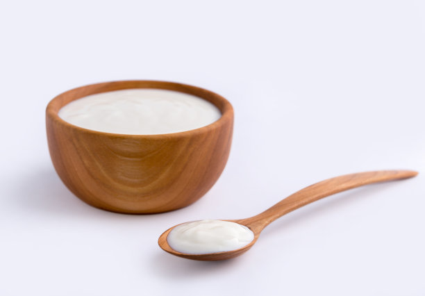 白色的酸奶在天然的木碗，白色的背景。图片下载