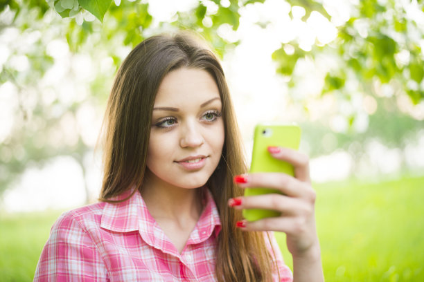 年轻的成年女子使用手机自拍图片下载