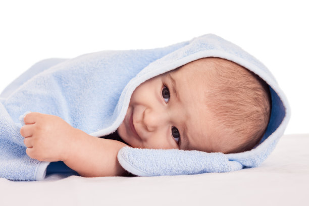 可爱的小宝贝躺在床上，披着蓝色的毛巾图片下载
