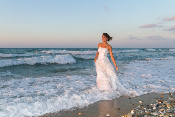 年轻的新娘喜欢黄昏时分在海滩上散步。图片下载