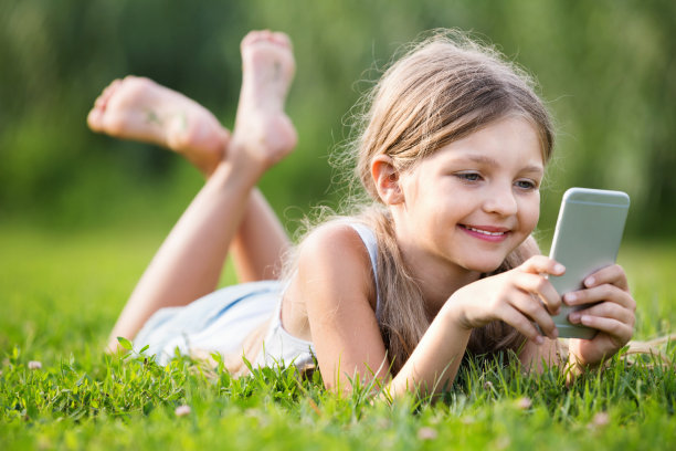 肖像女孩躺在公园里玩手机图片下载