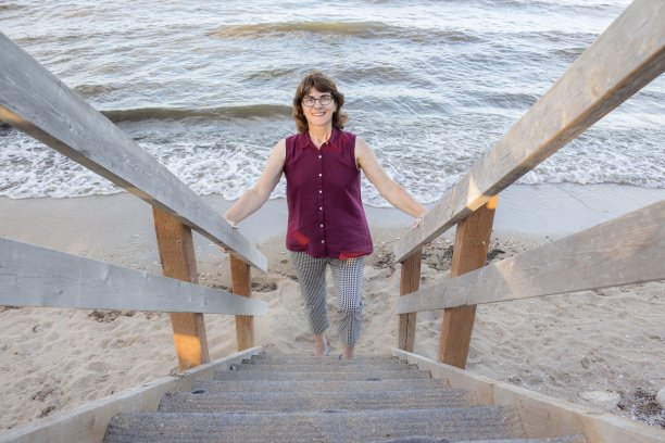 在海滩上爬木楼梯的女人。图片下载
