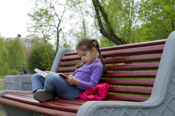 一个小女孩坐在长凳上看书图片下载