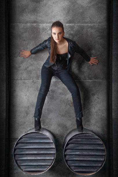 性感的黑衣女孩站在排气管上。图片下载