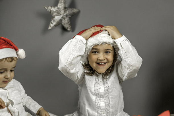 男孩和女孩戴着圣诞老人帽。躲躲猫。圣诞节的时间。图片下载