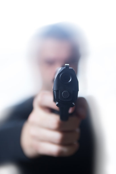 黑衣男子用手枪指着白人背景图片下载