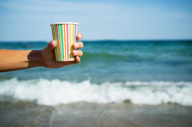 在大海的背景上，手拿咖啡纸杯图片下载