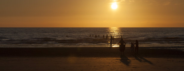 日落时人们在海里图片下载