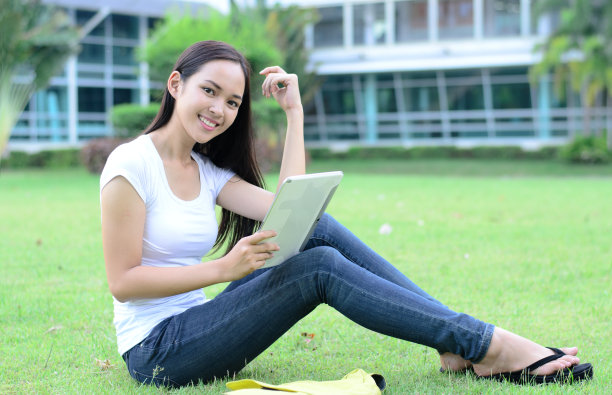 美丽的年轻学生在绿色的草地上休息图片下载