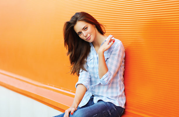 在夏天，漂亮的女人在户外，靠在彩色的墙壁上图片下载