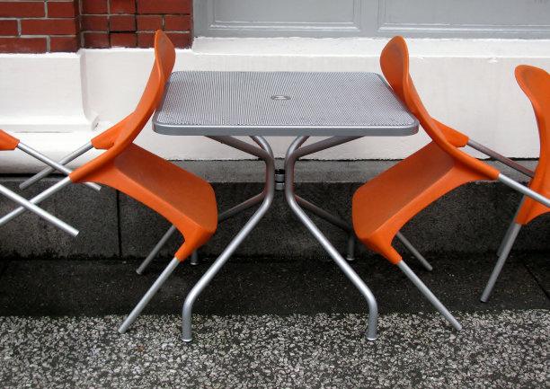 街头咖啡馆里的橙色椅子和灰色桌子。图片下载