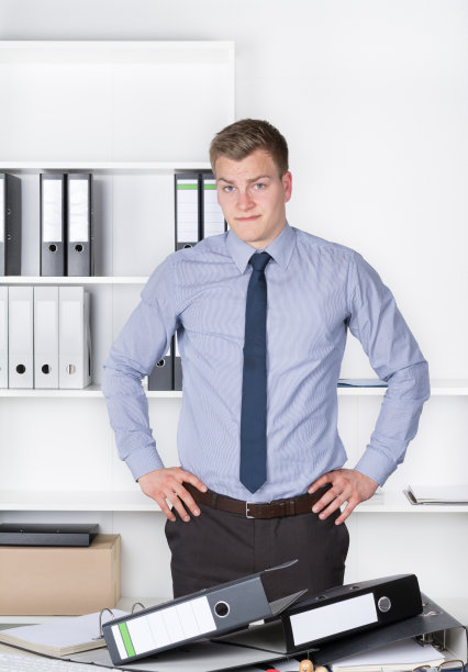 一个深思熟虑的年轻人站在许多文件的前面图片下载
