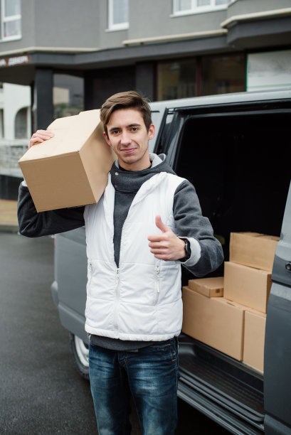 专业快递员附近的货车上放着纸箱。图片下载
