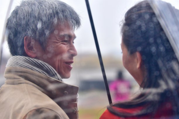 一对日本夫妇在京都加茂河边的伞下亲密交谈图片下载