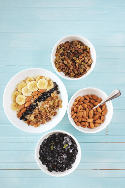 健康的早餐。白色碗里的燕麦片，香蕉，杏仁，蓝莓和葡萄干。图片下载