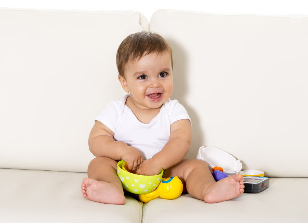 可爱的小婴儿坐在沙发上玩玩具图片下载
