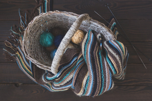 编织羊毛围巾和纱线球在柳条篮子在一个木材图片下载
