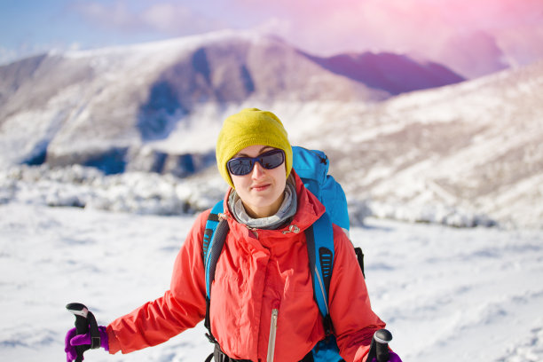 背着背包的女孩走在山上的雪地上。图片下载