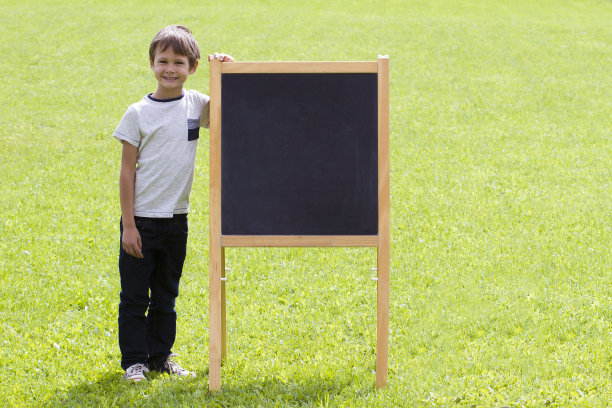 一个小男孩站在黑板附近。户外复印空间图片下载