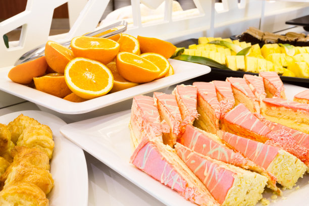 自助餐上有一盘粉红色糖衣的切片蛋糕图片下载