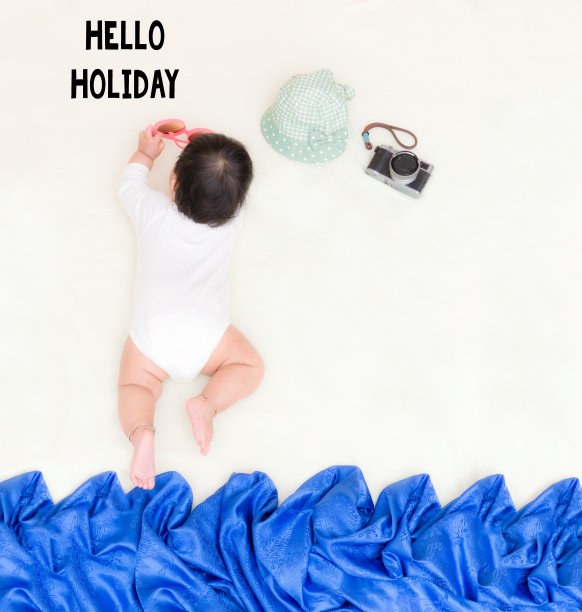 可爱的亚洲婴儿在毯子上晒日光浴HELLO假日信息。图片下载