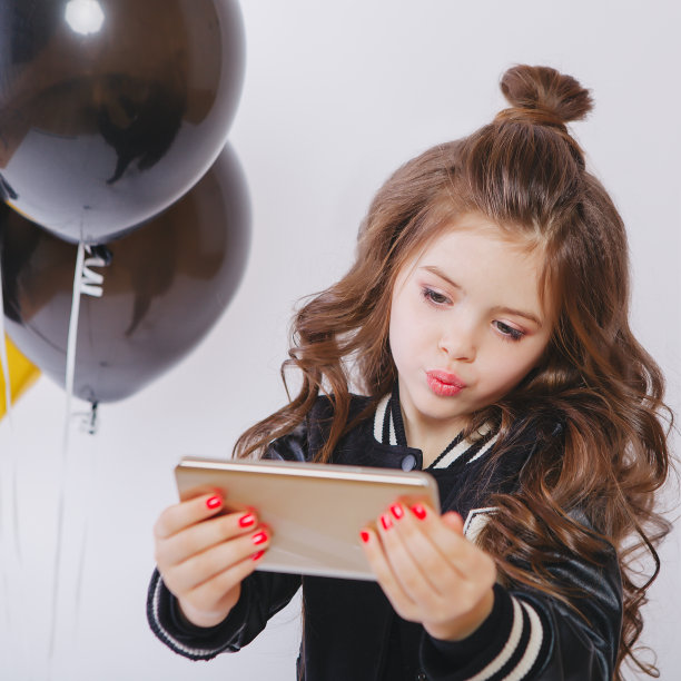 时髦的小女孩穿着时尚的衣服和气球，自拍图片下载