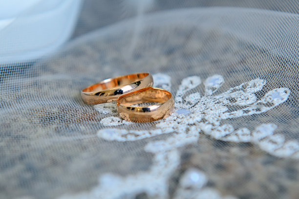 金色的结婚戒指戴在白色的蕾丝面纱上图片下载