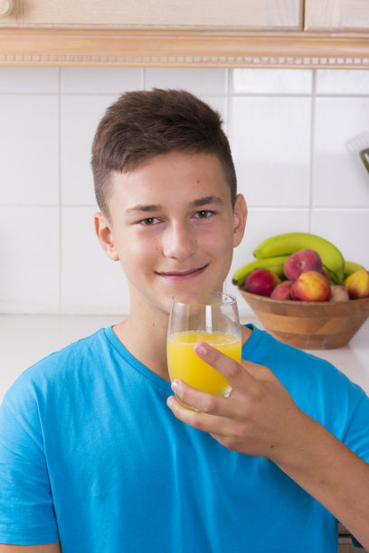 厨房里拿着一杯果汁的男孩图片下载