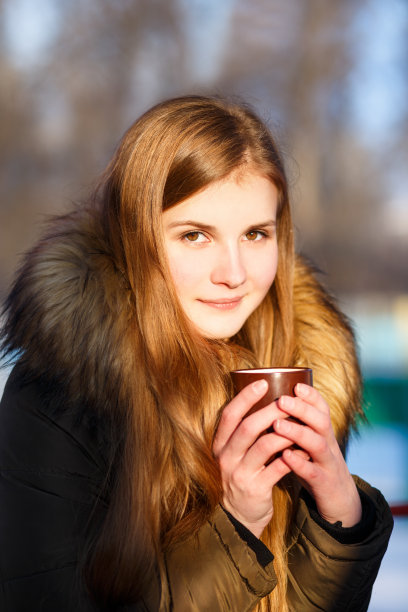 在冬天的公园里，年轻的女孩拿着一杯咖啡图片下载