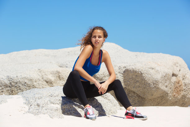 美丽年轻的女性跑步者放松在海滩图片下载