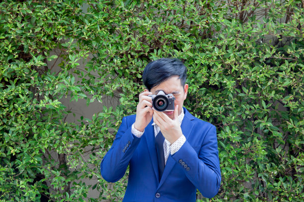 亚洲专业摄影师在绿色背景下拍照图片下载