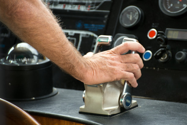 船长把手放在船的节流器上。素材图片