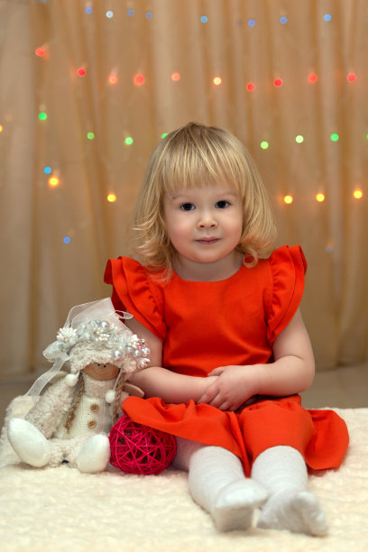 圣诞彩灯背景上有天使玩具的小女孩图片下载