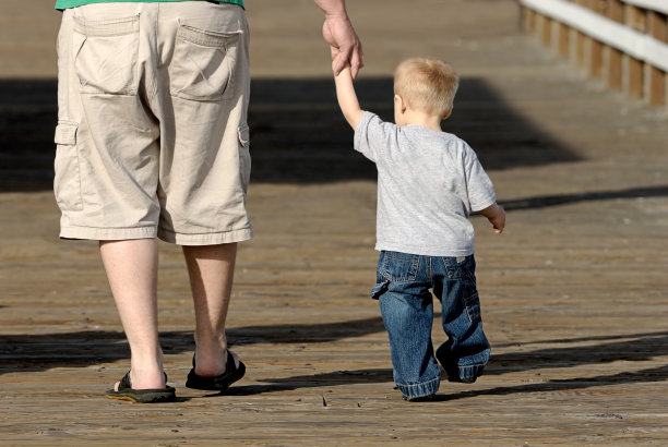 父亲和儿子手牵着手走在木制甲板上图片下载