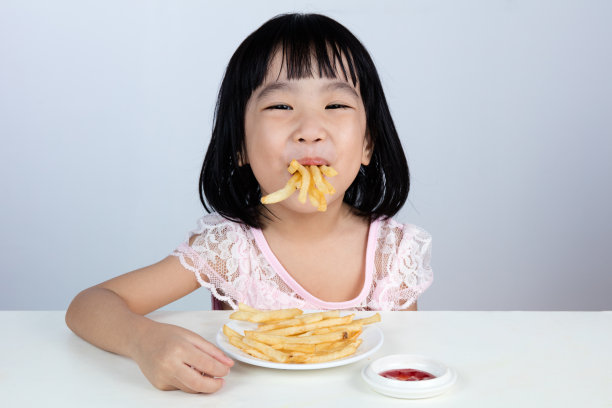 快乐的亚洲华人小女孩吃着炸薯条图片下载