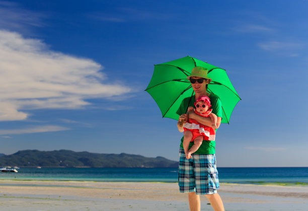 父亲和女儿带着雨伞去海滩度假图片下载