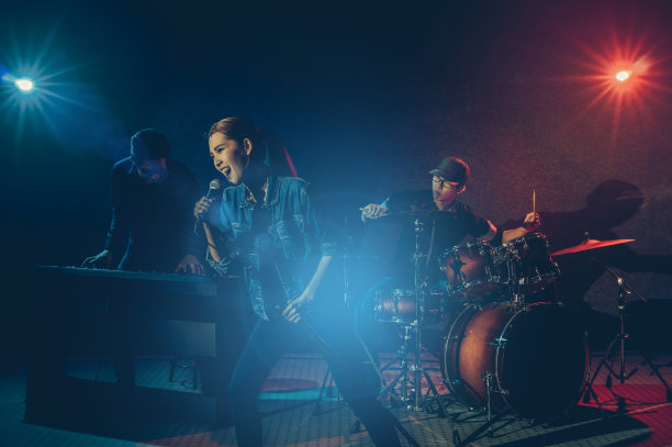 乐队手拿麦克风，唱着歌和演奏乐器与乐队的其他音乐家在黑色的背景与聚光灯和镜头眩光，音乐的概念素材图片