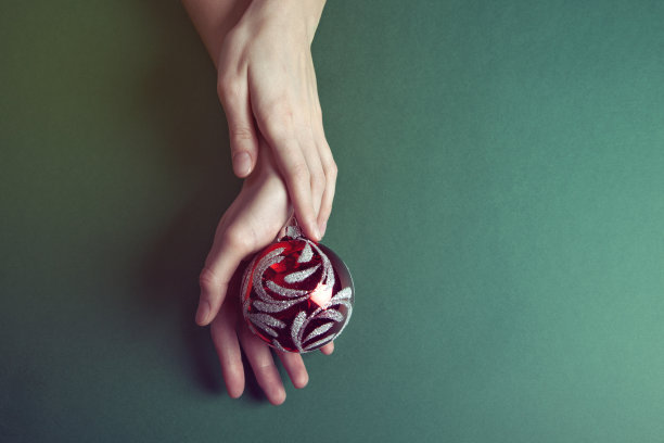 圣诞玩具在美丽的手在绿色的背景图片下载