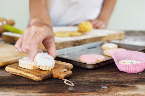 女孩双手把带爱心的蜜饯饼干放在木板上图片下载
