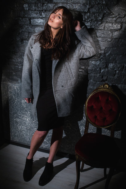 穿着灰色外套的漂亮女人站在深色的砖墙上图片下载