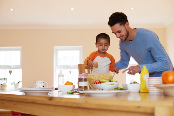 父亲和儿子在厨房里做意面沙拉图片下载