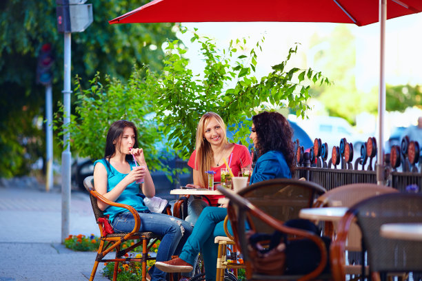 年轻的女性朋友坐在咖啡馆露台，城市户外图片下载