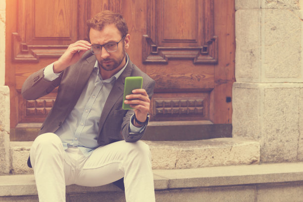 年轻英俊的男子使用智能手机。图片下载