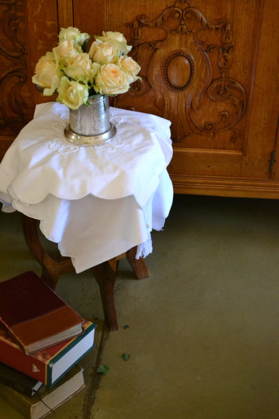 奶油玫瑰装在银罐子里，放在桌子上，旁边是书图片下载