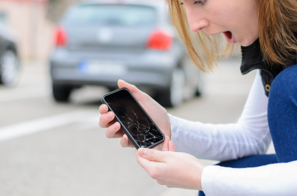 一个年轻女子捡起她被砸了的手机图片下载